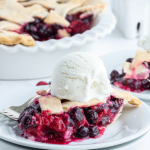 slice of raspberry blueberry pie on plate with ice cream