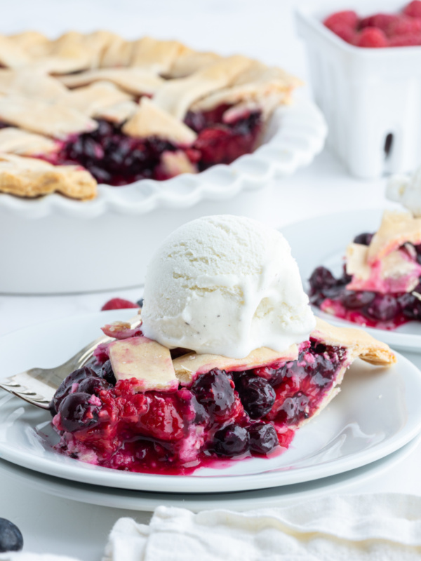 slice of raspberry blueberry pie on plate with ice cream