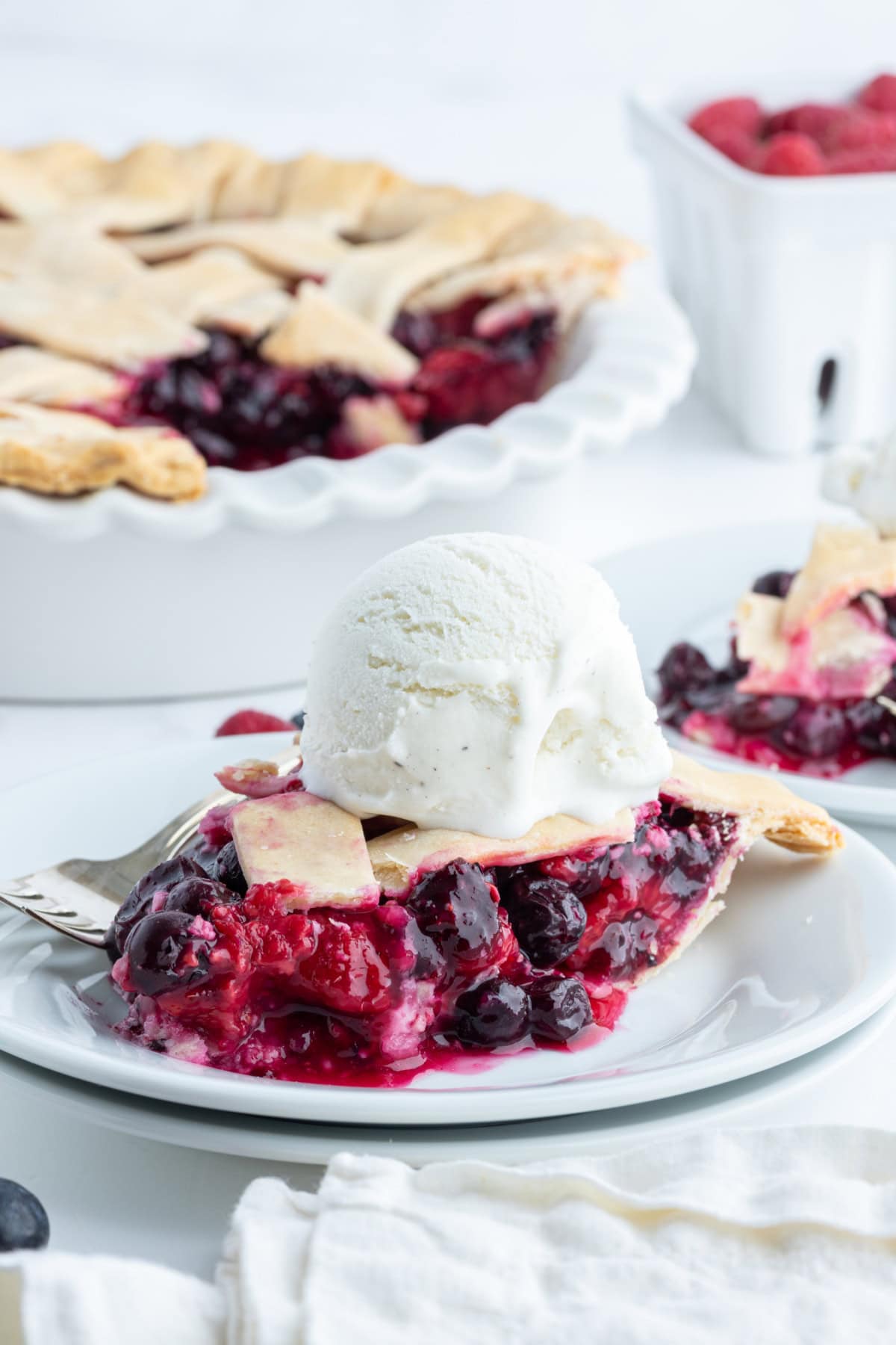 slice of raspberry blueberry pie on plate with ice cream