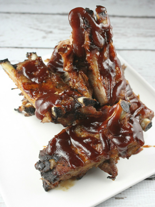 ribs on a white plate drizzled with barbecue sauce