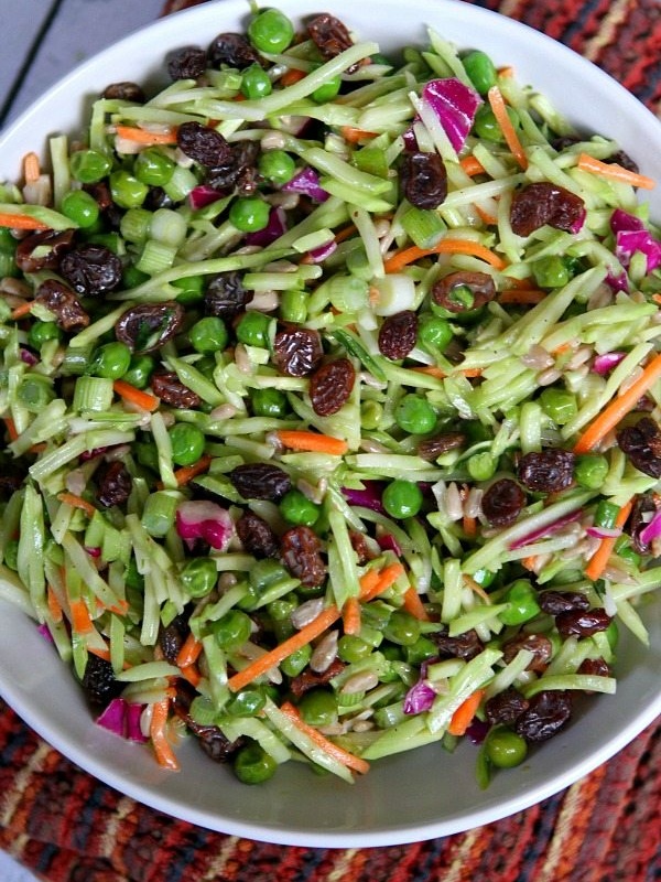 overhead shot of a bowl of broccoli slaw set on top of a burgundy striped cloth napkin