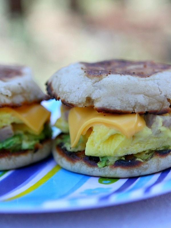 two camping breakfast sandwiches sitting side by side on a blue striped tablecloth