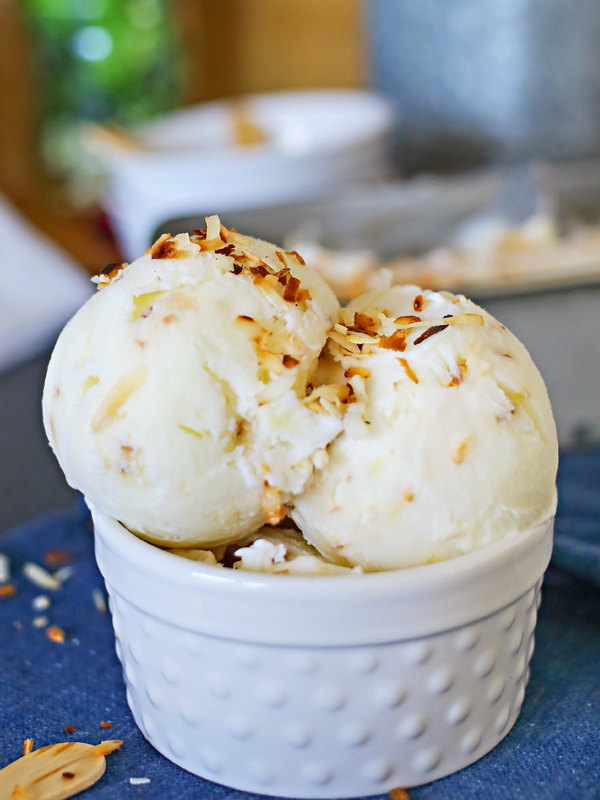 Coconut Frozen Yogurt scooped into a white serving dish sitting on a blue tablecloth