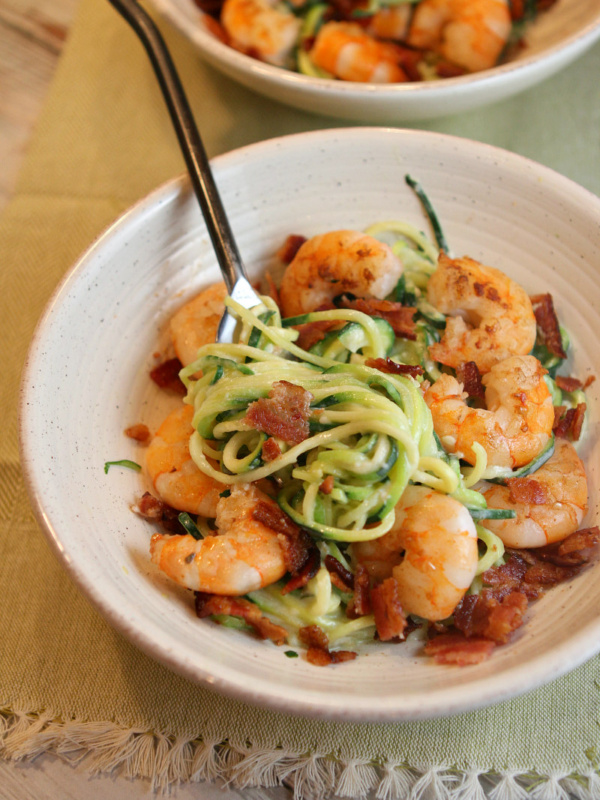 white bowl with fork of alfredo zoodles and shrimp