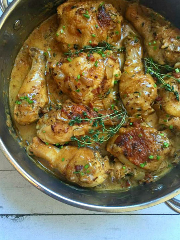 chicken pieces cooking in pan with sauce and fresh thyme