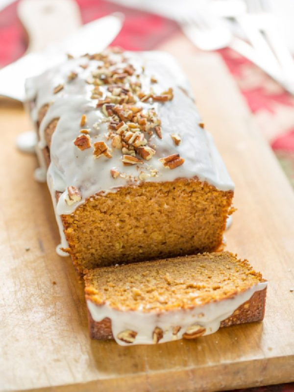 pumpkin loaf cake on cutting board with slice taken out of it