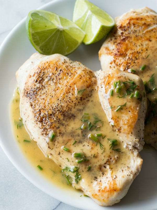 chicken topped with lime butter on a white plate with fresh lime wedges