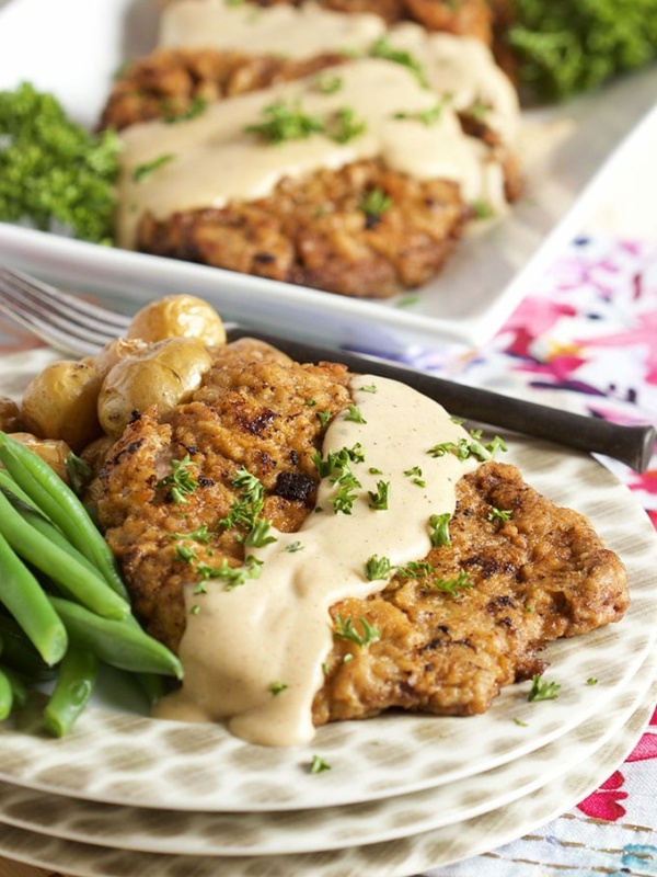 chicken fried steak with gravy on top and fresh green beans. Displayed on a polka dot stack of plates.