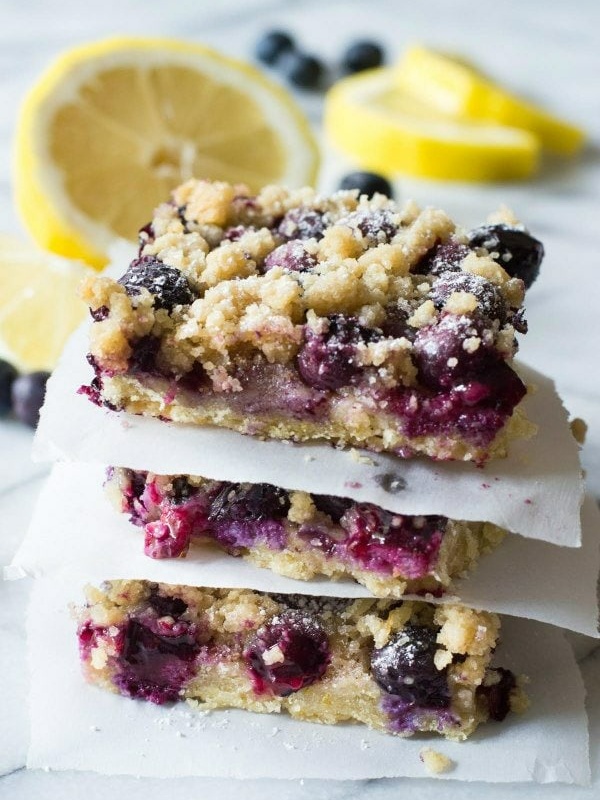 stack of blueberry lemon crumb bars with fresh cut lemons in background