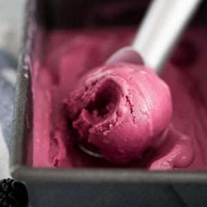 blackberry frozen yogurt being scooped out of a metal ice cream container