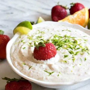 margarita fruit dip garnished with strawberries and lime, displayed in a white bowl on a marble surface