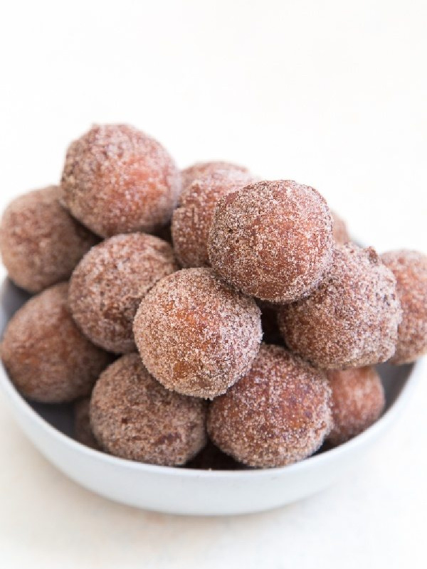 apple cider doughnut holes stacked in a white bowl