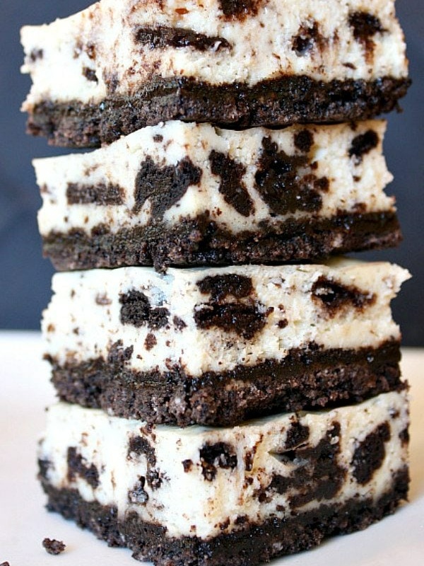 four pieces of cookies and cream cheesecake bars stacked on top of each other