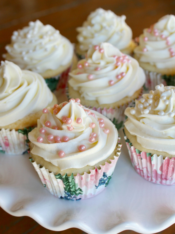 wedding cupcakes with white buttercream and pink pearls on a white cake platter