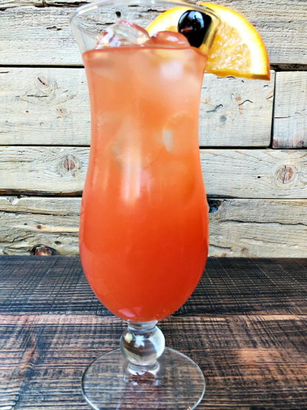 hurricane cocktail in a hurricane glass with a wooden background