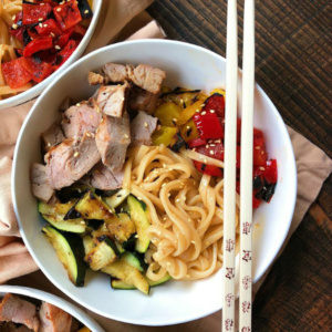 overhead shot of teriyaki pork noodle (white) bowls with a set of chopsticks set on top of one of the bowls.