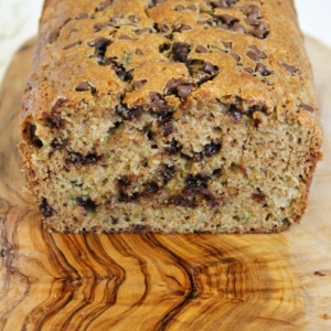 Loaf of chocolate chip zucchini bread cut open on a wooden cutting board