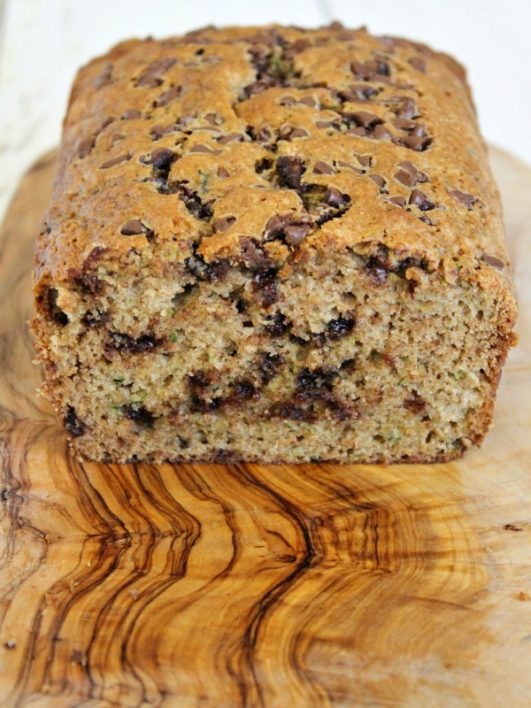 Loaf of chocolate chip zucchini bread cut open on a wooden cutting board