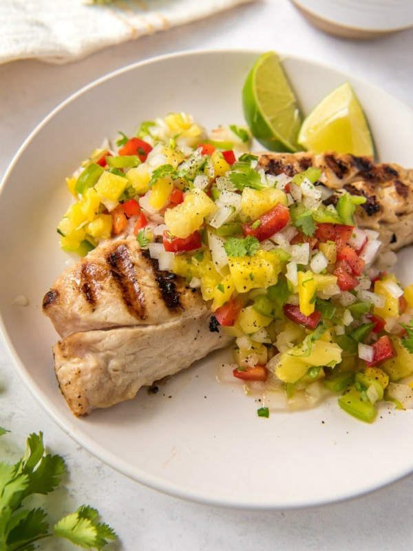 overhead shot of red snapper with pineapple salsa on a white plate with lime garnish