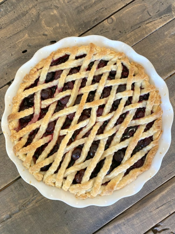 overhead shot of cherry amaretto pie with lattice pie crust on a wooden board