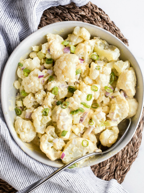 cauliflower potato salad in a white bowl on a striped napkin