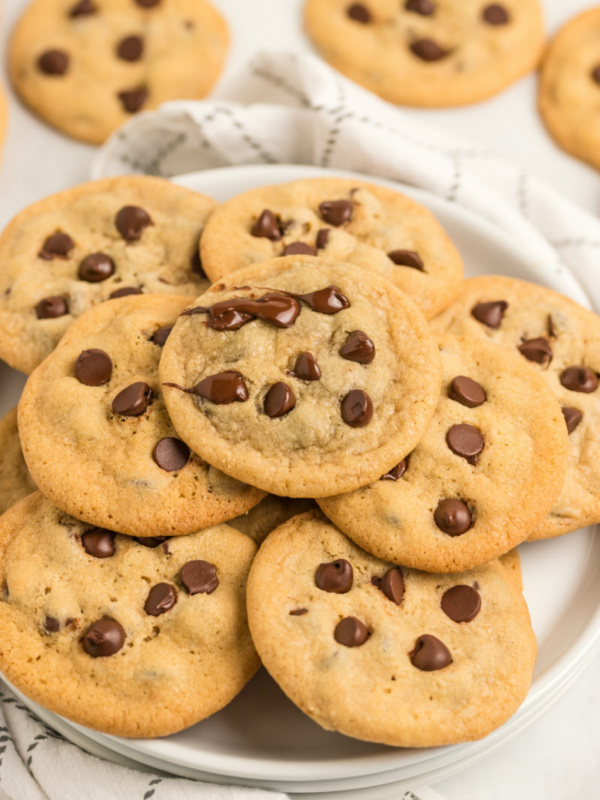 chocolate chip cookies displayed on a white platter on top of a white and gray plaid napkin