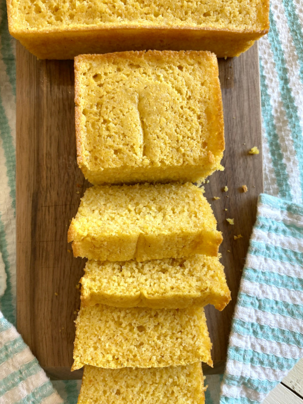 overhead shot of buttermilk cornbread sliced on a cutting board set on a white/teal striped cloth napkin