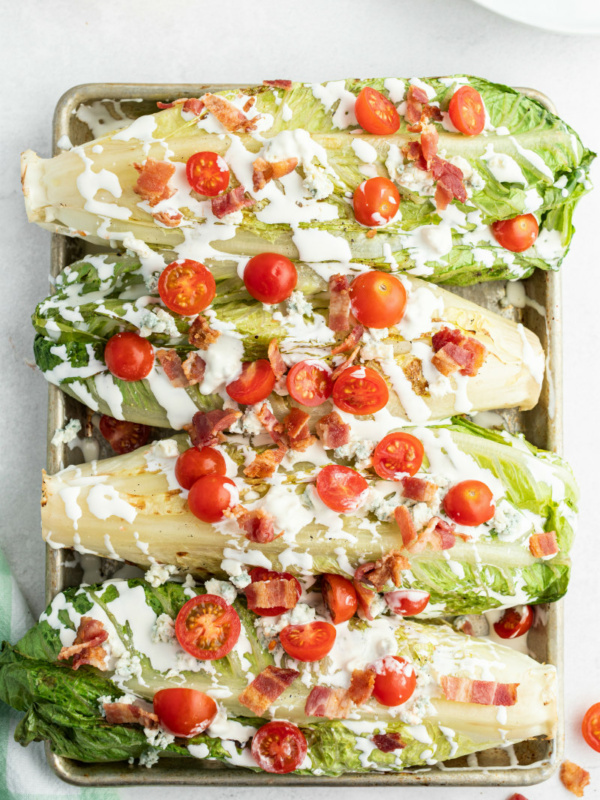 four grilled wedge salads displayed on a baking sheet