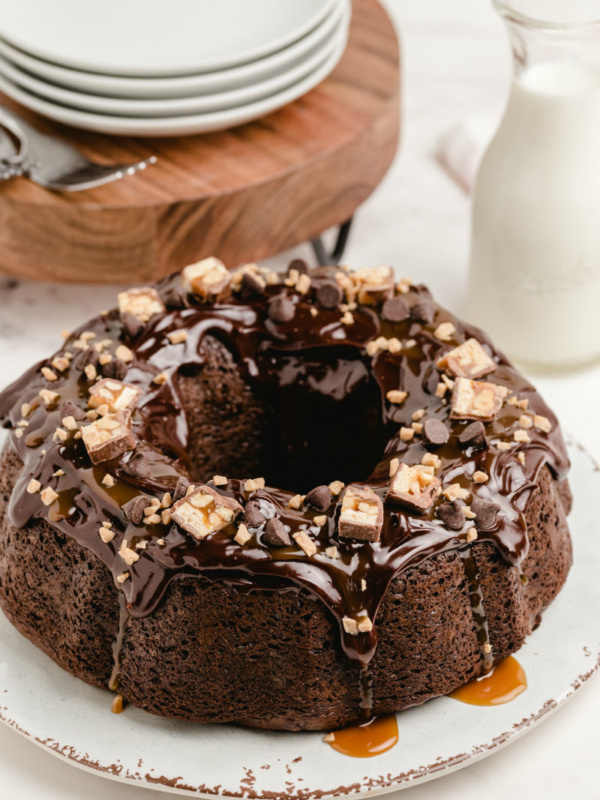 chocolate wasted cake displayed on a white plater with stack of white plates and milk in background