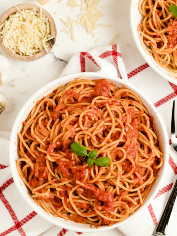 pasta pomodoro in a white bowl garnished with fresh basil