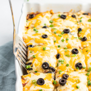 chicken enchilada casserole in a white dish with spatula