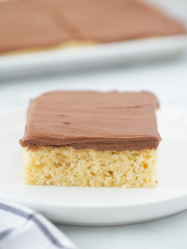 slice of yellow cake on a plate with chocolate frosting