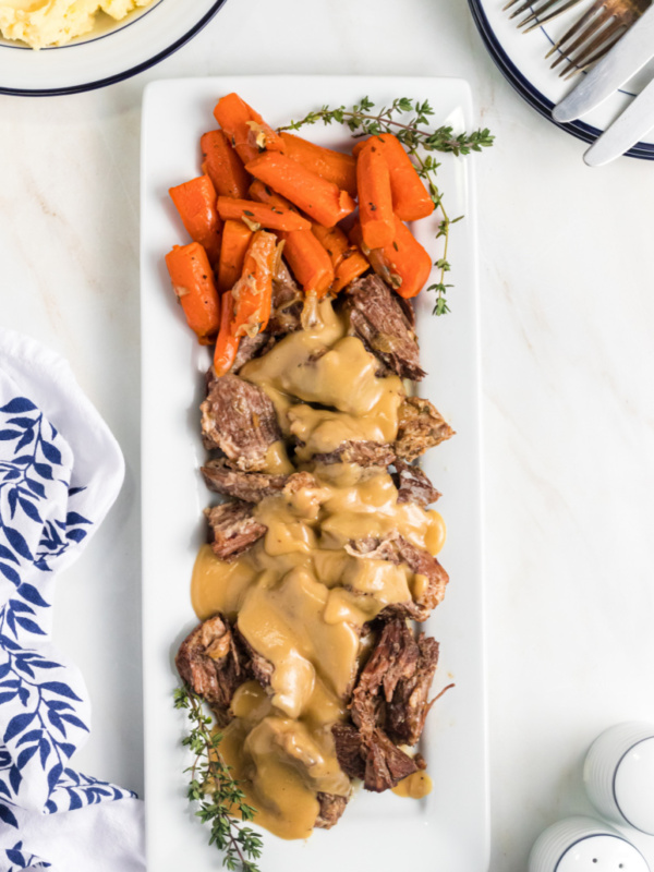 pot roast with gravy and carrots on a white platter