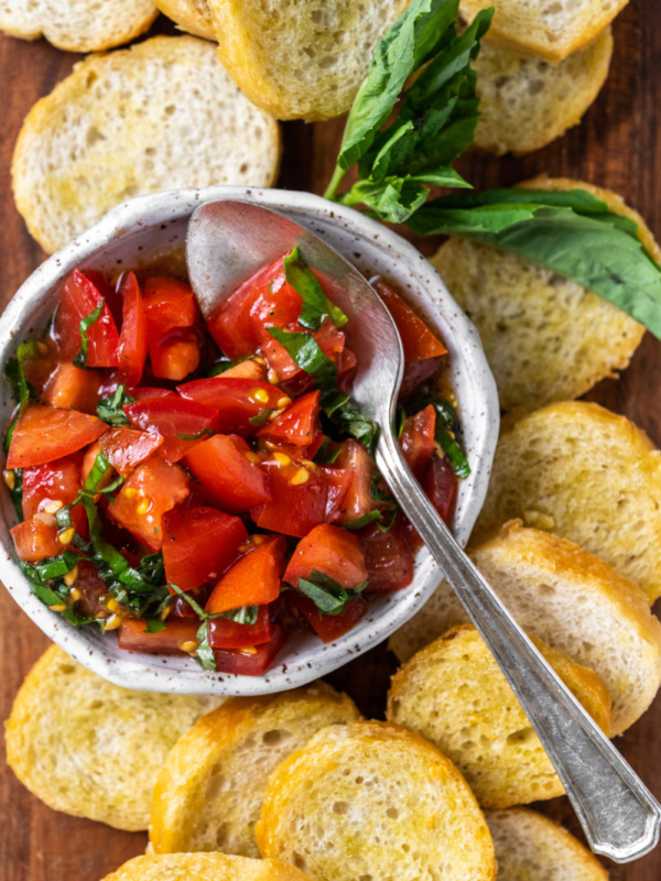 tomato bruschetta in bowl surrounded by baguette slices