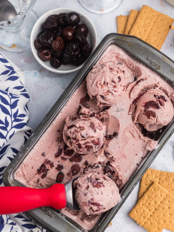 pan of cherry cheesecake ice cream with scoops on top and scooper