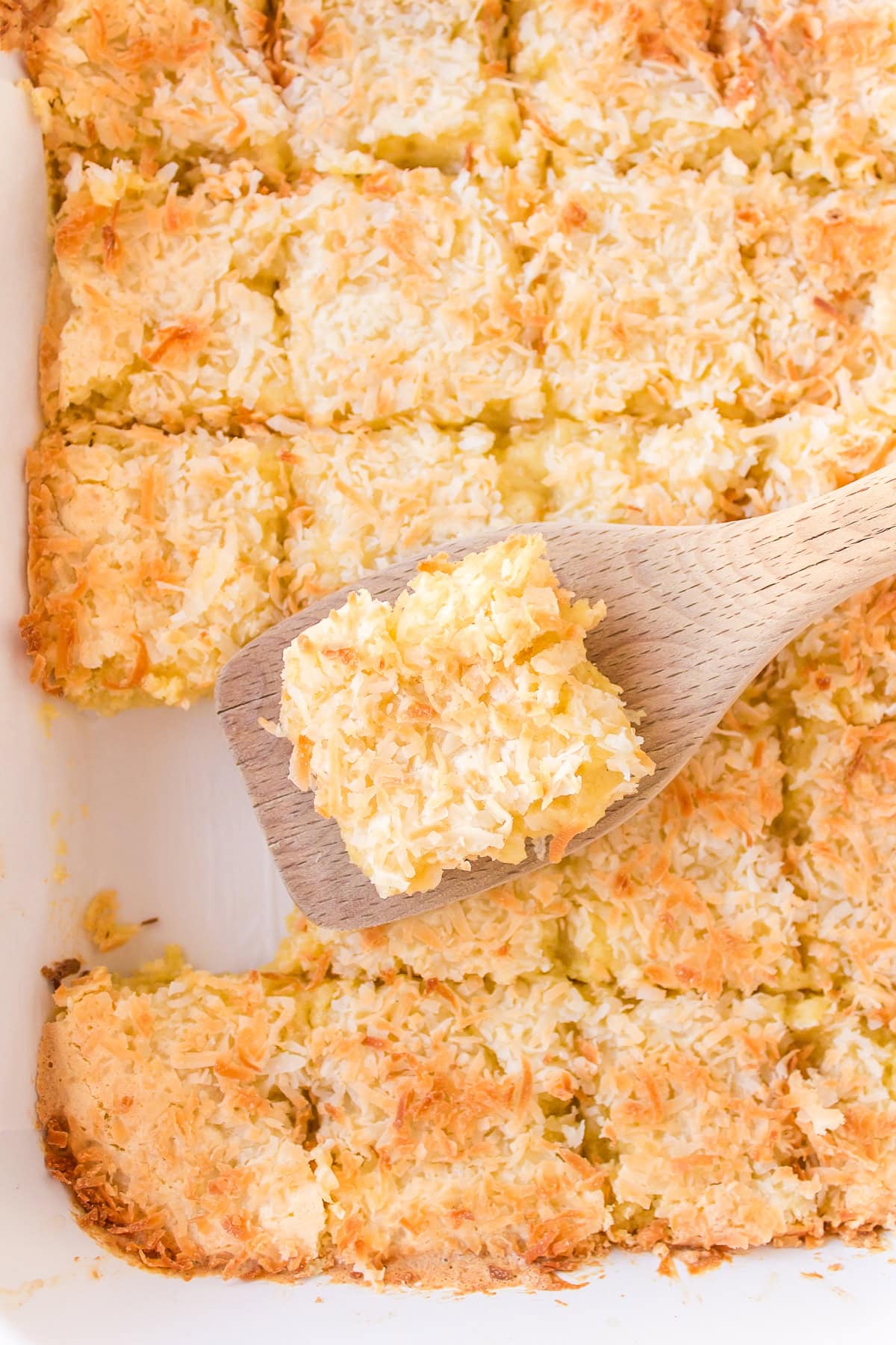 spatula taking almond coconut bar out of pan of bars