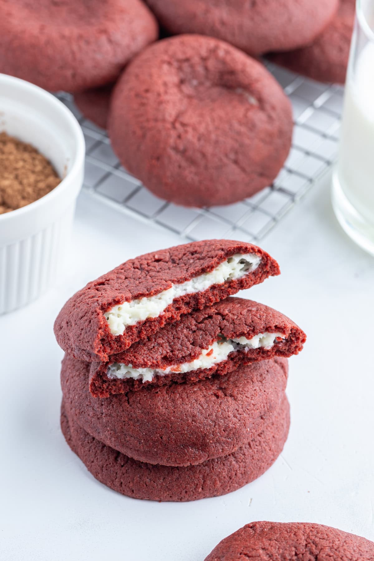 cheesecake stuffed red velvet cookies stacked and broken open to see inside