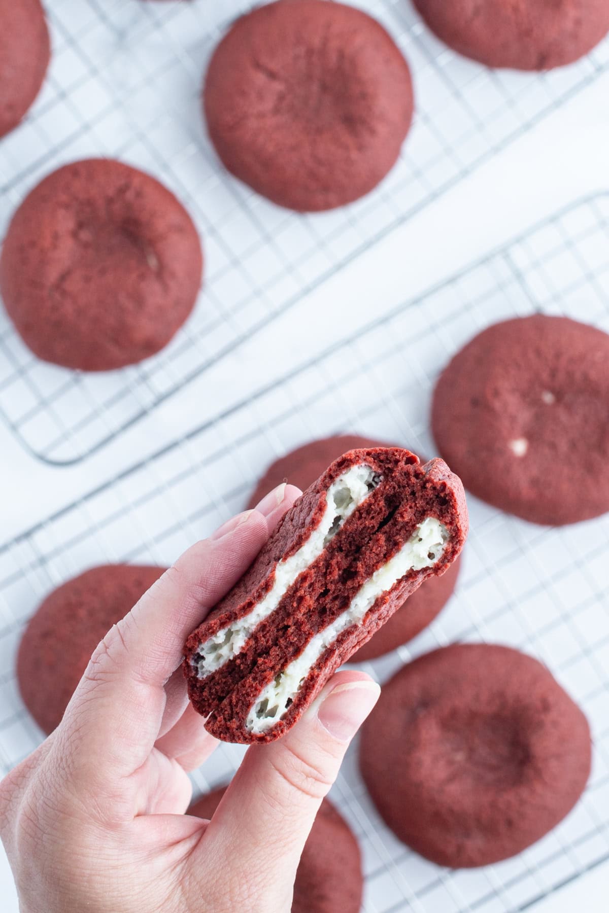 hand holding broken open cheesecake stuffed red velvet cookie