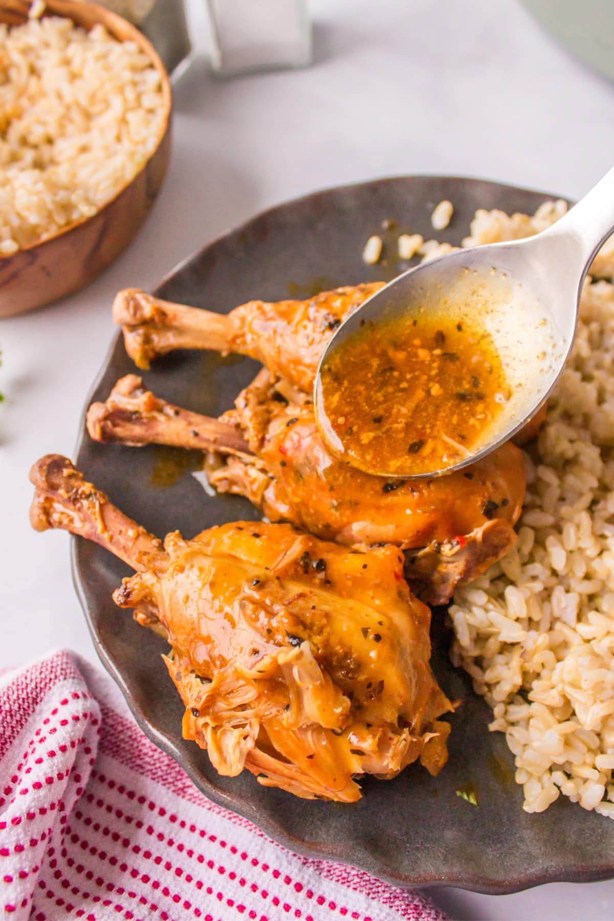 spooning sauce onto coconut chicken drumsticks on plate