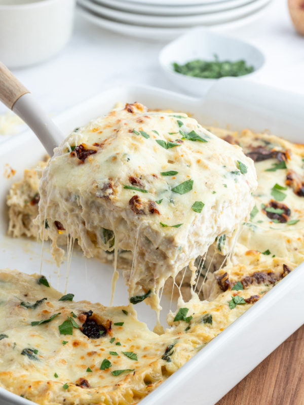 marry me chicken lasagna with spatula taking slice out of dish