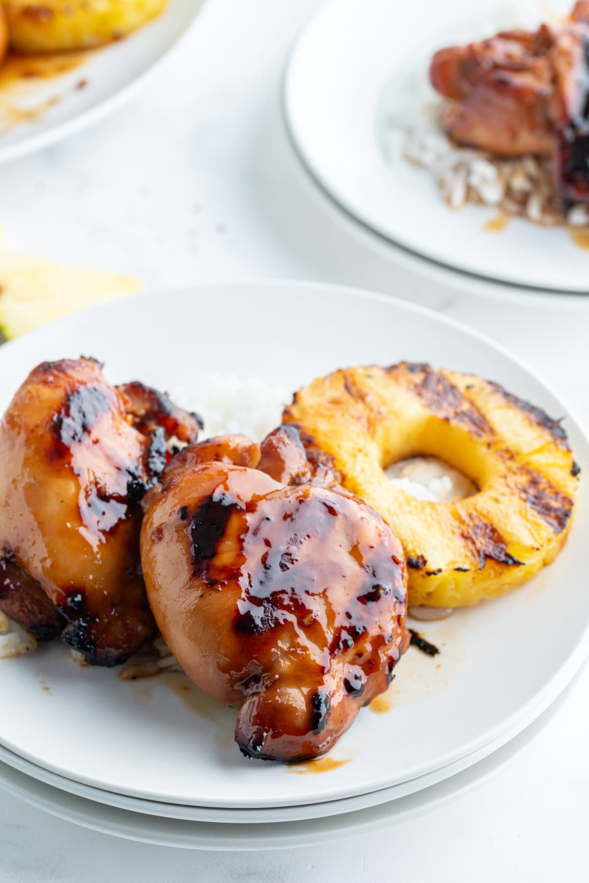 two pieces of grilled huli huli chicken on plate with pineapple