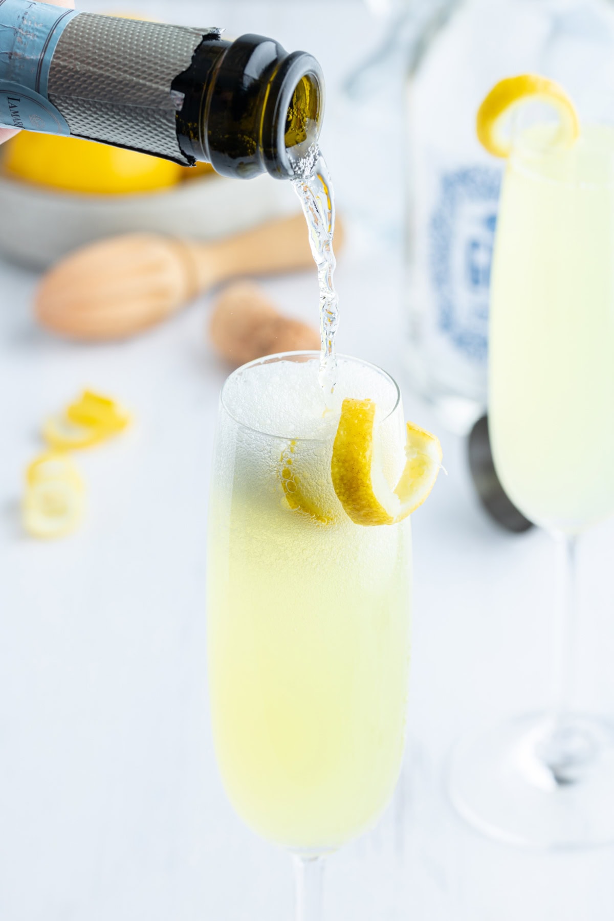 pouring sparkling wine into french 75 cocktail