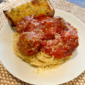 garlic bread meatballs in sauce on pasta on plate with garlic bread