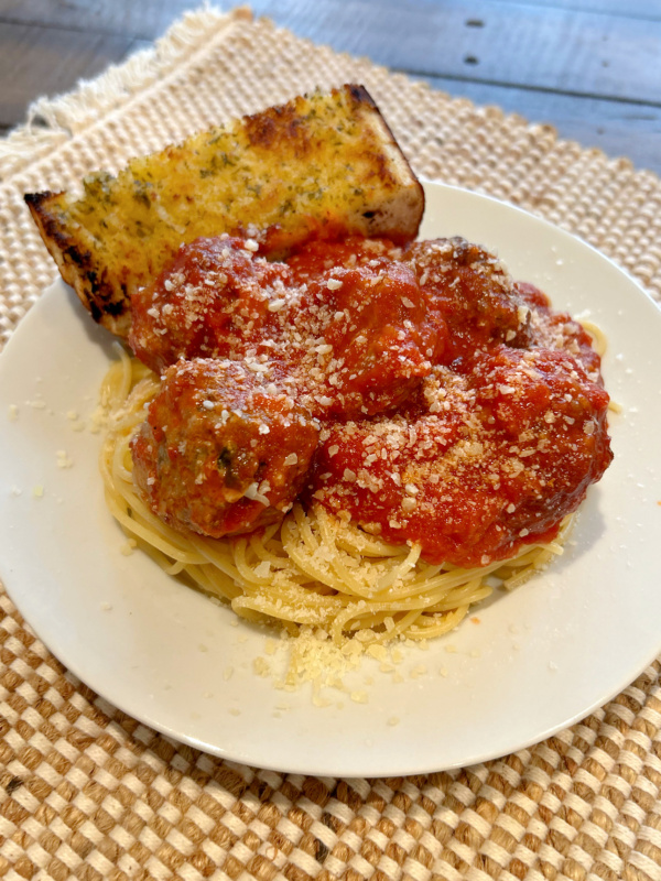 garlic bread meatballs in sauce on pasta on plate with garlic bread