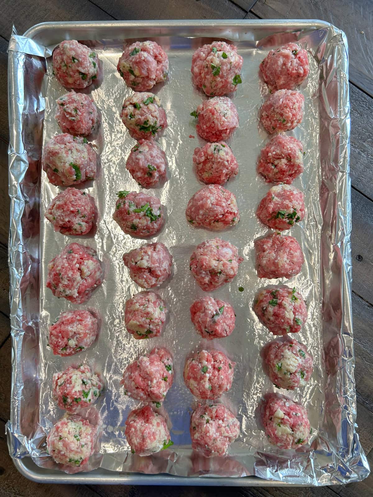 many meatballs on a baking sheet ready for oven