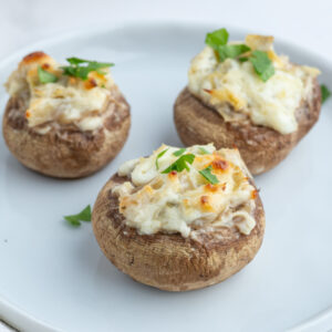 three artichoke stuffed mushrooms on plate