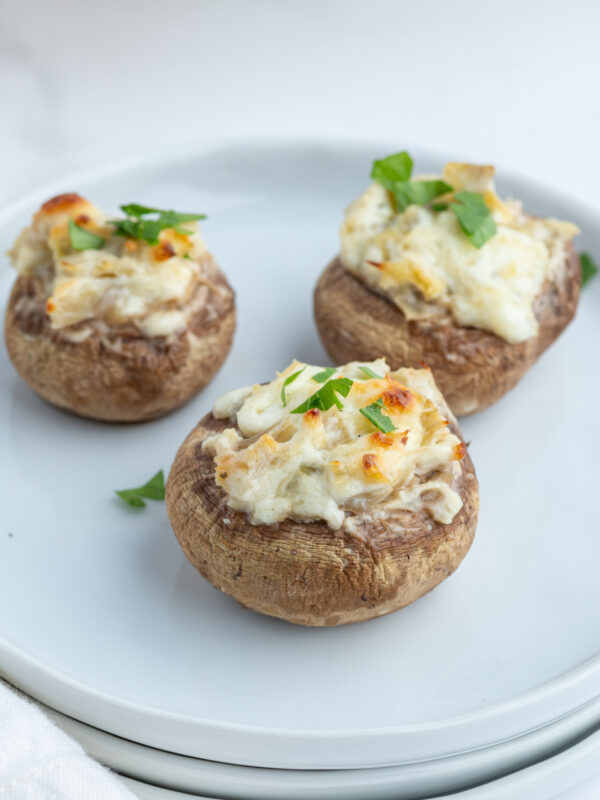 three artichoke stuffed mushrooms on plate