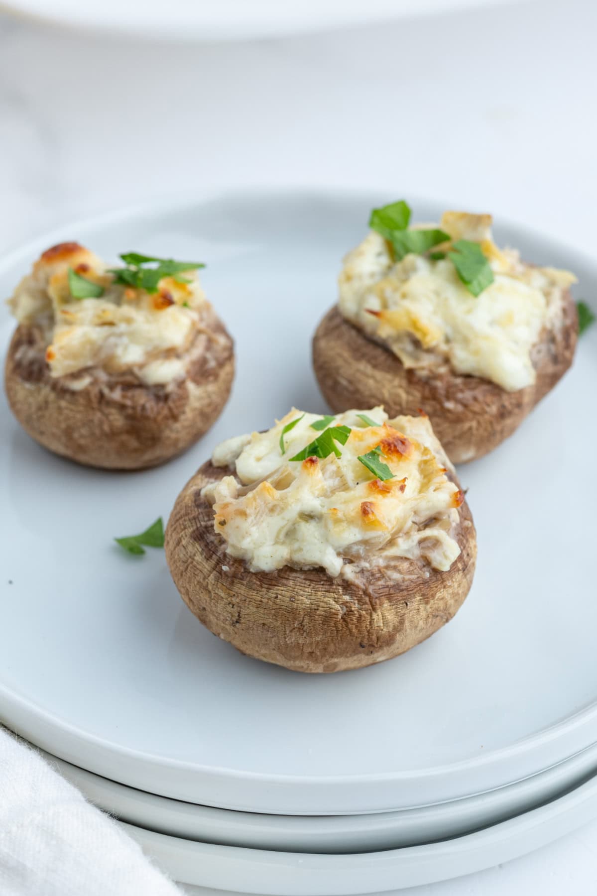 three artichoke stuffed mushrooms on plate