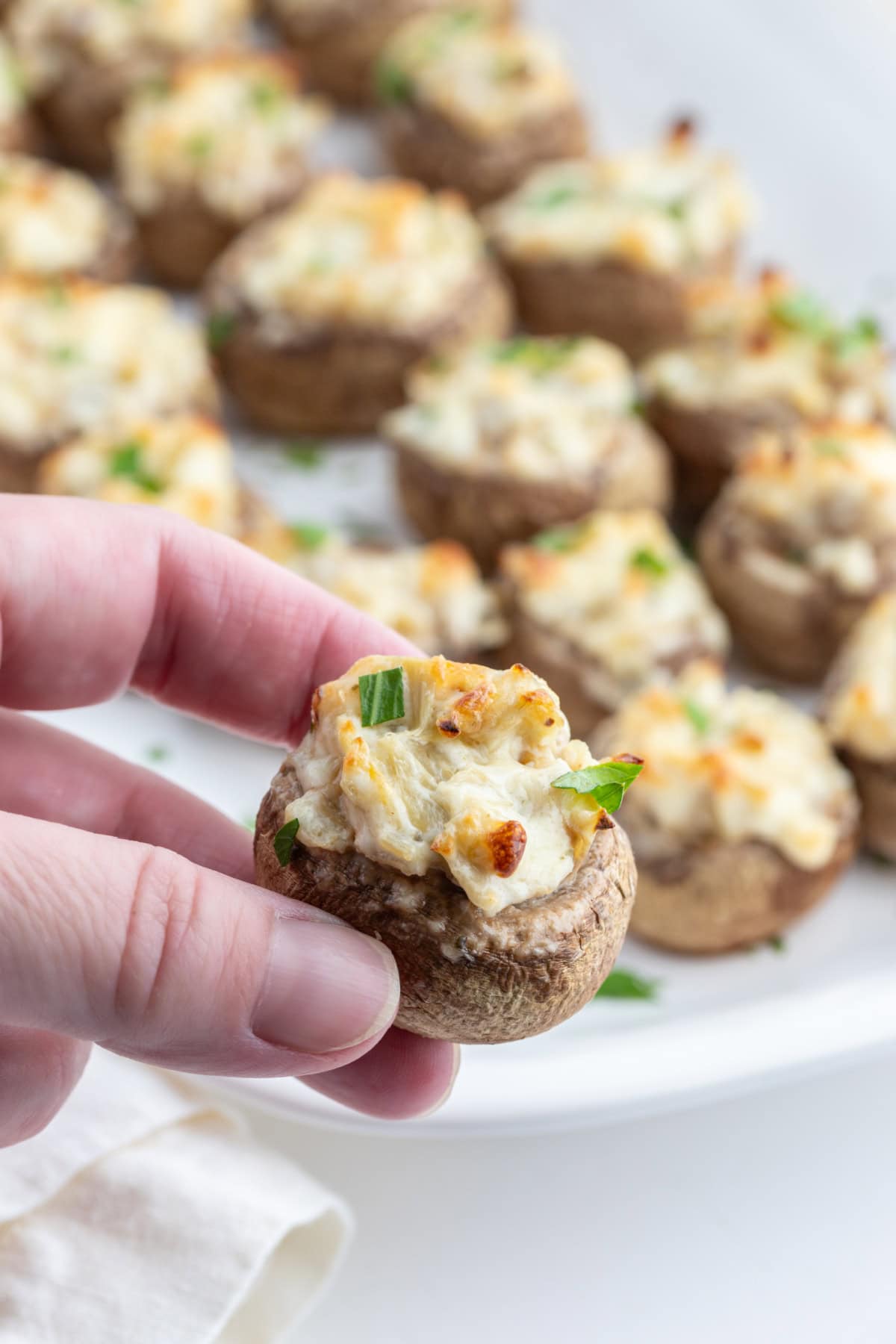 hand holding artichoke stuffed mushroom