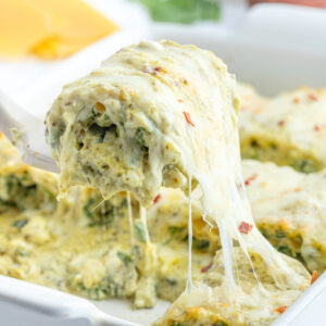 spatula pulling pesto lasagna roll from casserole dish